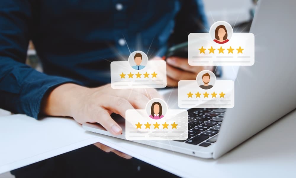 A lawyer using a laptop and mobile phone reads client reviews about their satisfaction and gives five-star ratings.