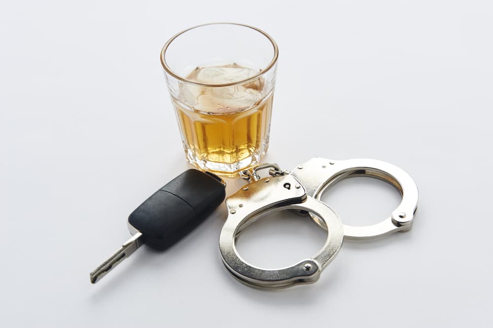 Handcuffs, whiskey, and keys isolated on a white background.