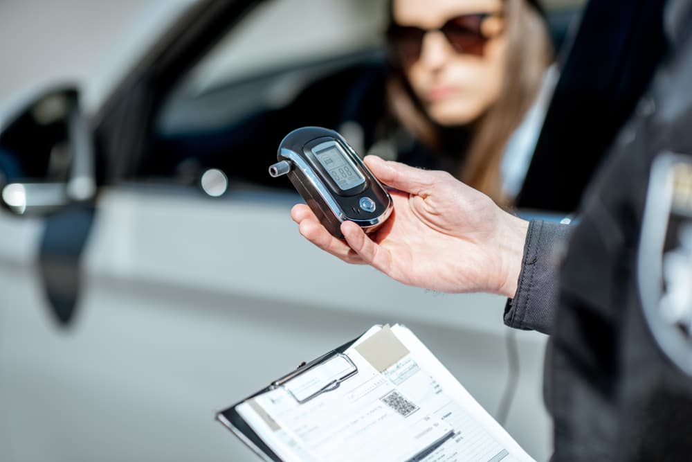 Policeman holding device for checking alcohol intoxication while standing near the stopped car