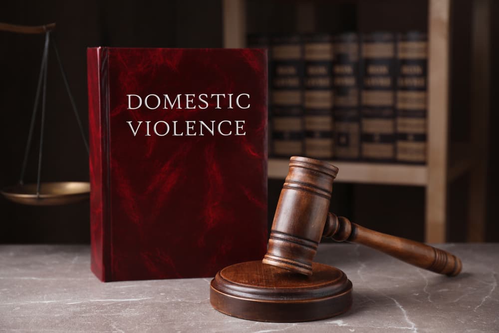 Domestic violence law and gavel on grey marble table.