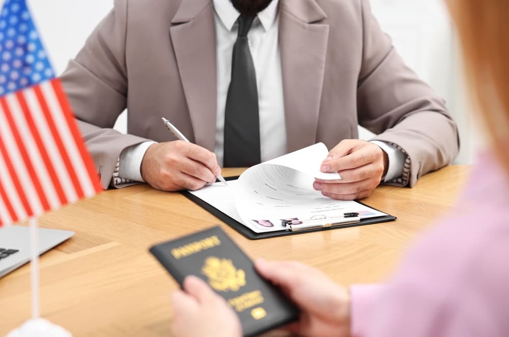 Immigration to the United States: Embassy worker approving a woman's visa application form in an office, close-up view.