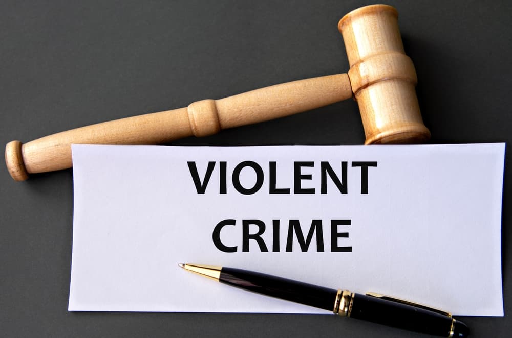 VIOLENT CRIME - words on white paper against a dark background with a judge's gavel. Information concept.