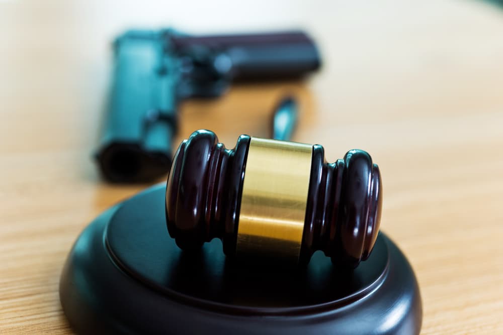 A gavel and gun on wooden table.