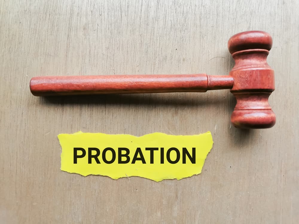 PROBATION written on yellow paper strip with gavel isolated on wooden background.